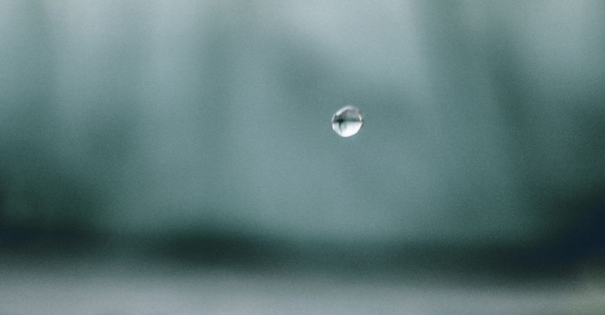 Goutte d'eau suspendue dans l'air avec un fond flou.